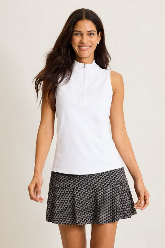 Woman wearing a white sleeveless top and black patterned skirt on a beige background