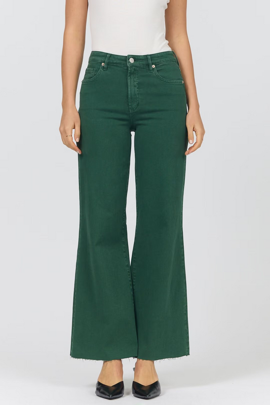 A model wearing a pair of dark green wide-leg cropped jeans with a frayed hem, paired with a white top and black pointed-toe heels, shown against a light gray studio background.