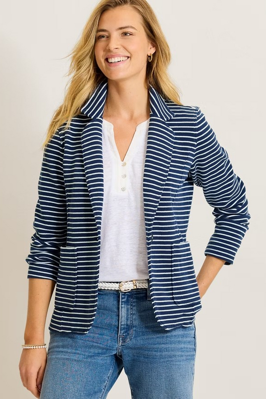 Woman wearing a blue and white striped blazer over a white shirt and jeans on a beige background